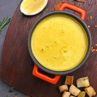 A bowl of soup with bread and lemon slices