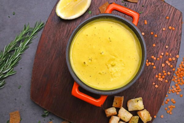 A bowl of soup with bread and lemon slices